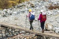 Couple Of Girls Are Hiking By Crossing The Bridge Over A Mountain River