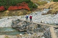 Couple Of Girls Are Hiking By Crossing The Bridge Over A Mountain River