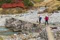 Couple Of Girls Are Hiking By Crossing The Bridge Over A Mountain River