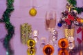 A couple of glasses with champagne on a wooden table with Christmas red balls, a glossy ribbon with a sprig of spruce on the backg