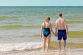 Couple going into sea with wave splashes