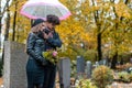 Couple in grief on a cemetery in fall