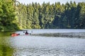 Couple of guy and a girl ride on red kayaks on the picturesque Round Lake in Lakamas forest