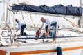 Two young men in blue shirts tidy up private sailing yacht in the seaport