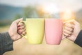 Couple hands clink hot coffee mug outdoor in the morning