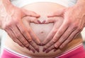Couple with hands in a heart shape on pregnant belly Royalty Free Stock Photo