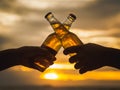 Couple hands holding beer bottles and clanging on the sunset beach. Party, Holiday, Summer, Friendship Concept. Royalty Free Stock Photo