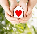 Couple hands holding white paper house