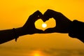 Couple hands making a heart love sign sillhoute during sunrise at a beach Royalty Free Stock Photo