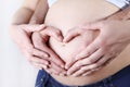 Couple hands making a heart shape on the pregnant belly Royalty Free Stock Photo