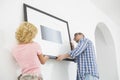 Couple hanging picture frame on wall in new house Royalty Free Stock Photo