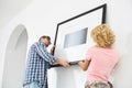 Couple hanging picture frame on wall in new house Royalty Free Stock Photo