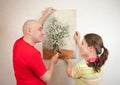 Couple hanging up an art picture on their wall