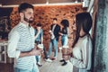 Couple of happy colleagues talking while standing at the office brick wall with cups of coffee Royalty Free Stock Photo