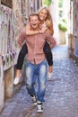 Couple, happy or piggyback on street in city, fun support or romance in committed relationship. Excited man, woman and