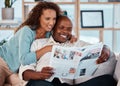 Couple, happy and reading newspaper in home, living room and check article information. Man, woman and smile in house Royalty Free Stock Photo