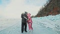 Couple has fun during winter walk against background of ice of frozen lake. Lovers lie on clear ice, have fun, kiss and Royalty Free Stock Photo