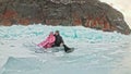 Couple has fun during winter walk against background of ice of frozen lake. Lovers lie on clear ice, have fun, kiss and Royalty Free Stock Photo