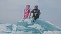 Couple has fun during winter walk against background of ice of frozen lake. Lovers lie on clear ice, have fun, kiss and Royalty Free Stock Photo