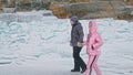 Couple has fun during winter walk against background of ice of frozen lake. Lovers lie on clear ice, have fun, kiss and Royalty Free Stock Photo