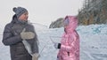 Couple has fun during winter walk against background of ice of frozen lake. Lovers lie on clear ice, have fun, kiss and Royalty Free Stock Photo