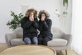 Couple have cold on the sofa at home with winter coat Royalty Free Stock Photo