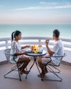 Couple having breakfast on balcony looking out over the ocean, Asian woman and Europe man on vacation in Thailand Royalty Free Stock Photo