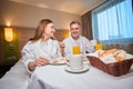 Couple having breakfast and looking at each other on bed at table in hotel room Royalty Free Stock Photo