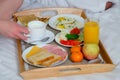 Couple having a breakfast together in bed in hotel, wooden tray closeup. Royalty Free Stock Photo