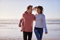 Couple Having Fun Running Along Winter Beach Together Royalty Free Stock Photo