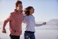 Couple Having Fun Running Along Winter Beach Together Royalty Free Stock Photo