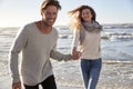 Couple Having Fun Running Along Winter Beach Together Royalty Free Stock Photo