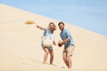 couple having fun on sand dune and throw hat forwards Royalty Free Stock Photo