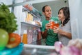 couple having a glass of juice in front of the open fridge Royalty Free Stock Photo