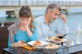 Couple having meal both preoccupied with cellphones