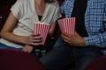 Couple having popcorn while watching movie in theatre