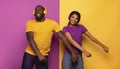 Couple with headset listen to music and dance with energy on violet and yellow background