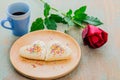 Couple of heart shape white bread on wooden plate with coffee cup and red rose