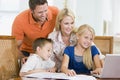 Couple helping children with laptop doing homework Royalty Free Stock Photo