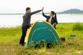 Couple helping installing tent camping outdoor near river and meadow.