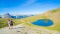 Couple of hiker on the mountain top looking at blue lake and mountain peaks. Summer adventures on the Alps. Wide angle view from a Royalty Free Stock Photo