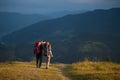 Couple hikers with backpacks holding hands, walking in the mountains Royalty Free Stock Photo