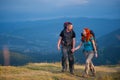 Couple hikers with backpacks holding hands, walking in the mountains Royalty Free Stock Photo