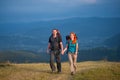 Couple hikers with backpacks holding hands, walking in the mountains Royalty Free Stock Photo