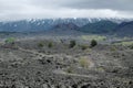 Couple hikers on the path to extinct cinder cones under the majestic volcanic cone of Etna Mount that is covered by clouds