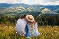 Couple of hikers relaxing sitting in Carpathian mountains enjoying landscape. Travelers kiss. Summer vacation