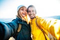 Couple of hikers taking a selfie climbing mountains - Man and woman with backpack smiling at camera - Bright filter Royalty Free Stock Photo