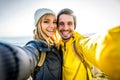 Couple of hikers taking a selfie climbing mountains - Man and woman with backpack smiling at camera - Bright filter Royalty Free Stock Photo