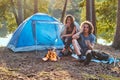 Couple hiking at in the forest. Attractive couple warming near a campfire at camp.