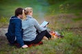 Couple hiking. Young couple sitting on grass near the fire embracing and examining the map. Travel, vacation, holidays and Royalty Free Stock Photo